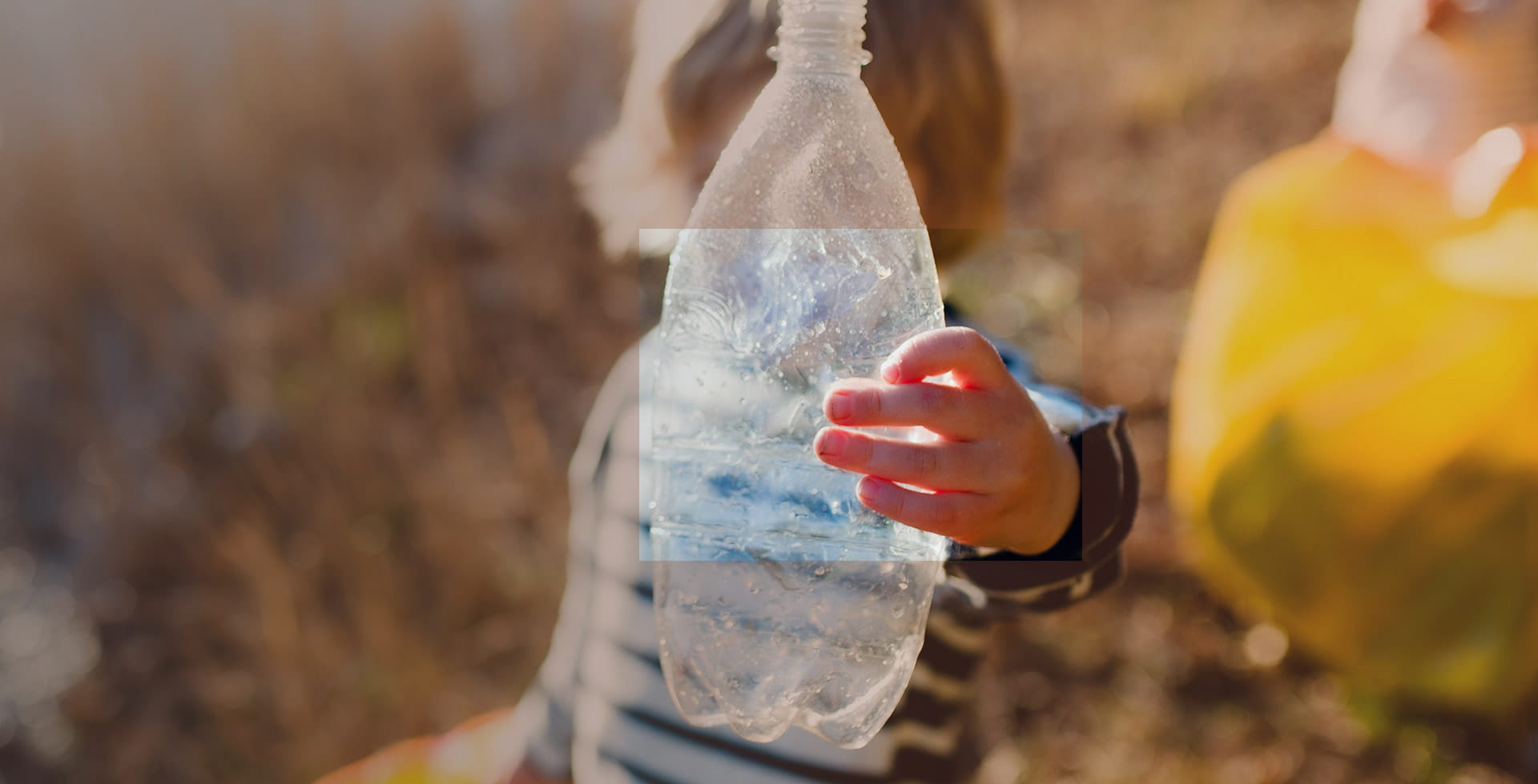 Kind das eine Plastikflasche gegen die Sonne hält – Nachhaltige Verpackungen – ein Bereich mit Zukunft