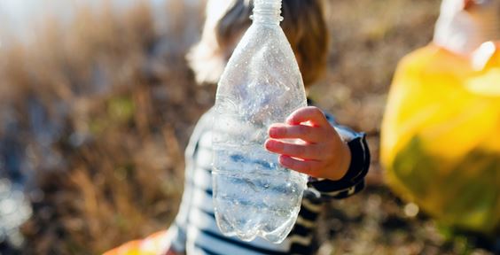 Kind das eine Plastikflasche gegen die Sonne hält – Nachhaltige Verpackungen – ein Bereich mit Zukunft